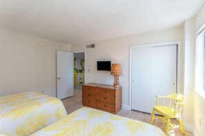 A bedroom with two beds, a dresser, a chair, a television, and a door. - Beautifully Renovated 2 Bedroom Ocean Front Condo! Fountainhead Towers 1201 (Ocean City)
