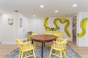 A dining area with a round wooden table, four yellow chairs, and a floral-patterned rug. - Beautifully Renovated 2 Bedroom Ocean Front Condo! Fountainhead Towers 1201 (Ocean City)