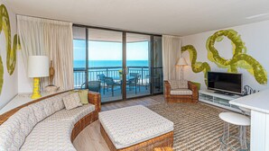 Un balcone con vista sul mare, un divano, una TV e un'area pranzo.