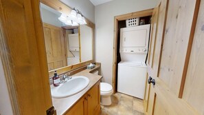 Ein kleines Badezimmer mit Waschbecken, Spiegel, Toilette und einer kleinen Waschmaschine.