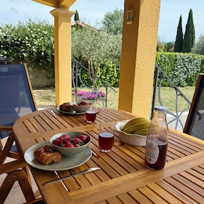 A wooden table with a breakfast setting including croissants, strawberries, a glass of juice, and a bottle of drink. - Whole family house with 3 bedrooms, garden and swimming pool. Ardèche gorges (Vallon-Pont-d'Arc)