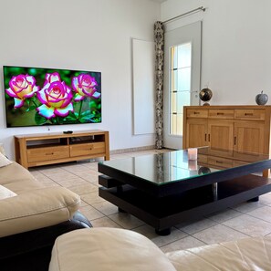 A living room with a flat-screen TV, a glass coffee table, a wooden cabinet, and a sofa. - Whole family house with 3 bedrooms, garden and swimming pool. Ardèche gorges (Vallon-Pont-d'Arc)