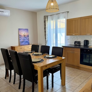 A modern kitchen with wooden cabinets, a dining table set for four, and a painting on the wall. - Whole family house with 3 bedrooms, garden and swimming pool. Ardèche gorges (Vallon-Pont-d'Arc)