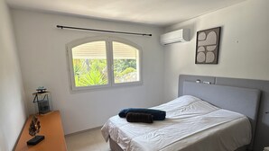 Ett sovrum med en säng, ett skrivbord, ett fönster och en luftkonditioneringsanläggning.