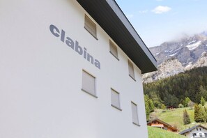 A building with the name 'Clabina' on its facade, featuring multiple windows and a mountainous backdrop. - Bright apartment with superb terrace and view (Leukerbad)