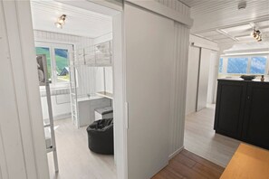 Et værelse med skydedør til en balkon, et tekøkken, en sort puf og et sort skab.