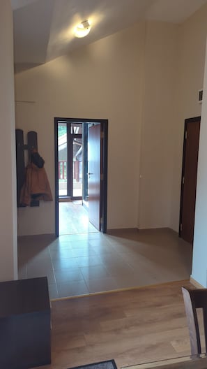 Un hall dâentrĂ©e spacieux, dotĂ© dâun sol carrelĂ©, dâun escalier en bois et dâune porte donnant sur lâextĂ©rieur.