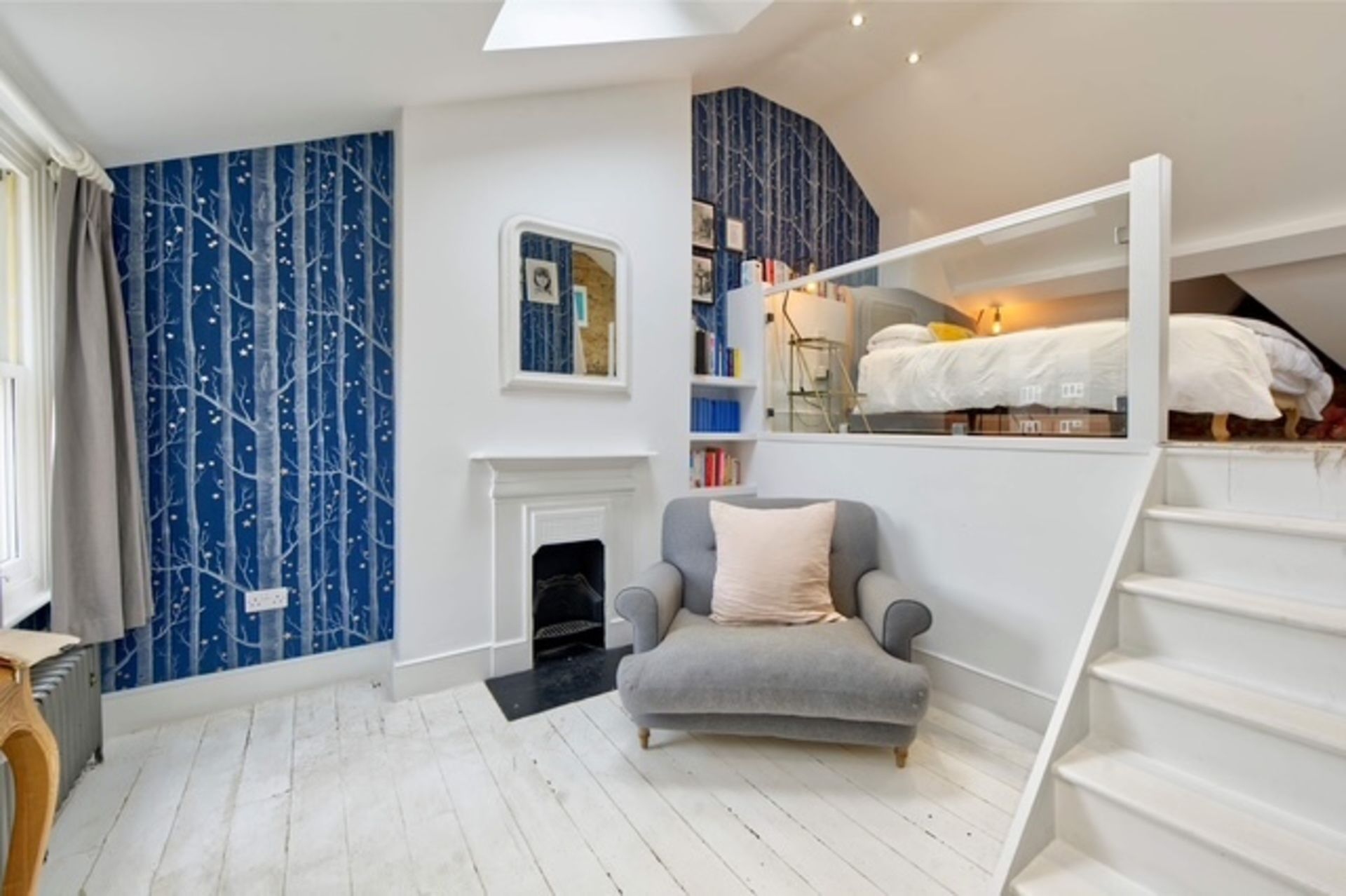 A bedroom with a bunk bed, a fireplace, a chair, and a bookshelf.