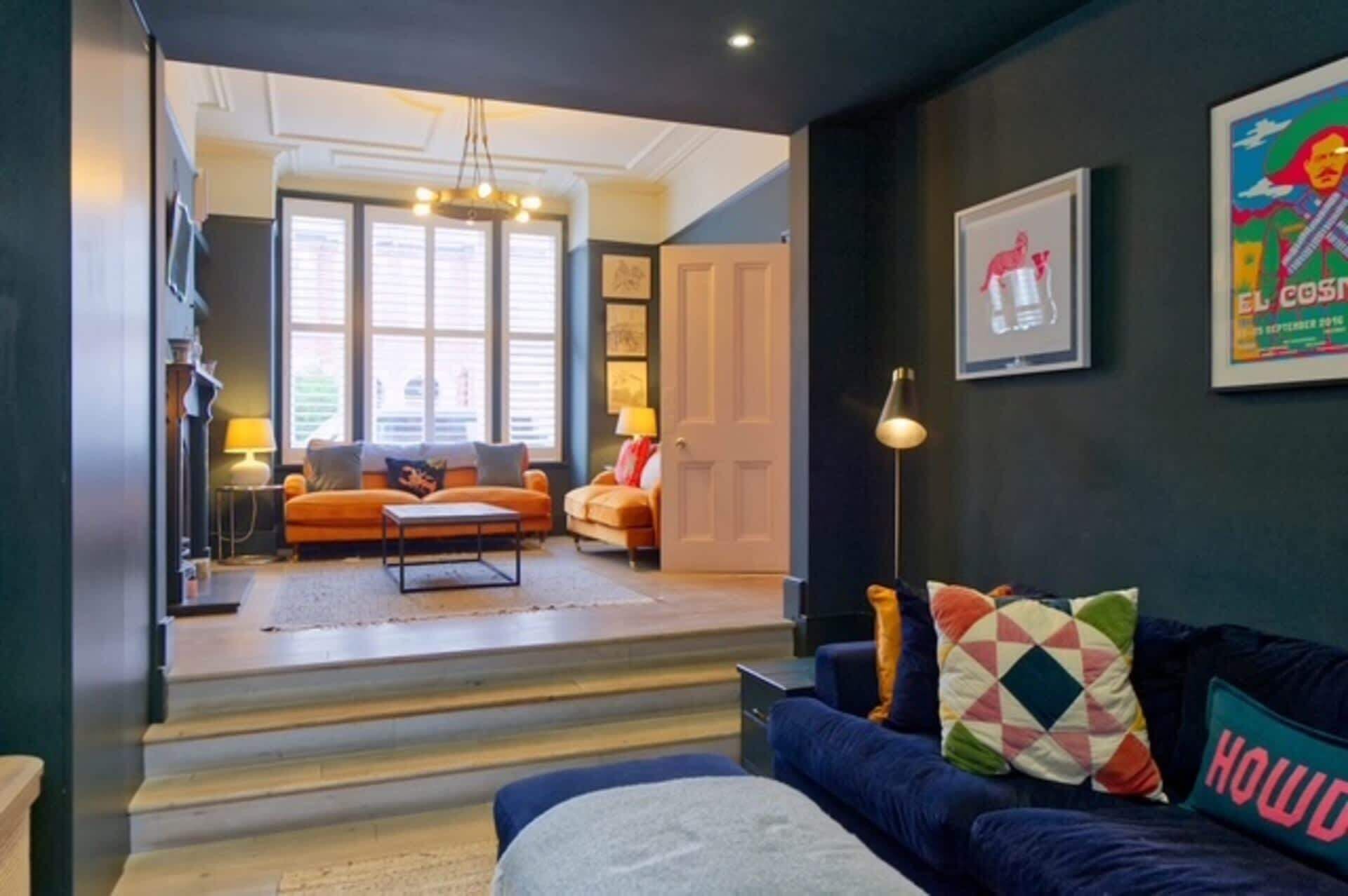 A modern living room with a sofa, a coffee table, and a lamp. There is a staircase leading to another room.