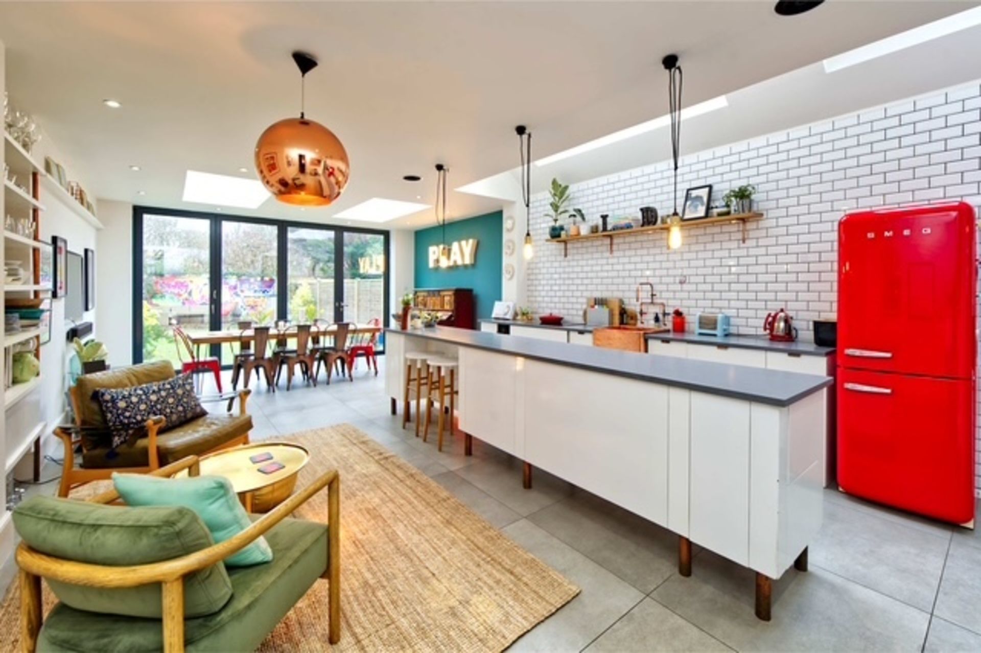 A modern kitchen with a red refrigerator, white cabinets, and a dining area with a table and chairs.