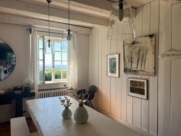 A kitchen with a large window, white wooden walls, and hanging pendant lights. - Charming property, family home, panoramic ocean view, large, quiet garden (Plouarzel)
