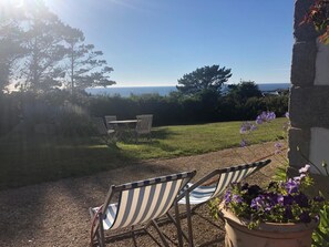 A patio with two striped chairs, a table, and a view of the sea. - Charming property, family home, panoramic ocean view, large, quiet garden (Plouarzel)