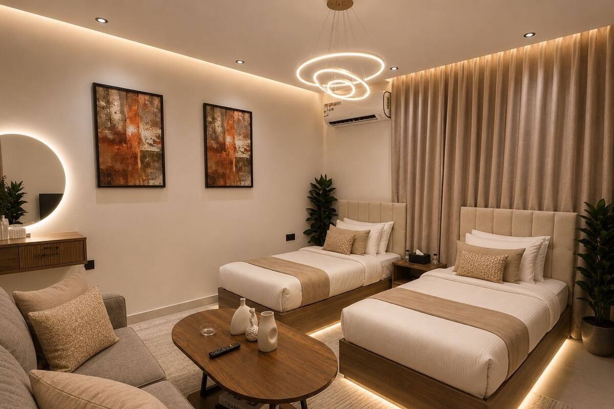 A modern hotel room with two beds, a sofa, a coffee table, and artwork on the walls.