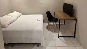 Une petite pièce propre, avec un lit, un bureau et une chaise.