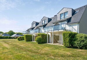 A row of modern houses with balconies, a well-maintained lawn, and a clear sky. - Scenic 6-person Duplex Retreat (Île-aux-Moines)