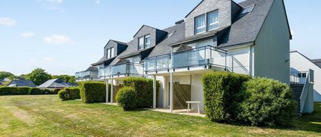A modern two-story house with a balcony and a covered patio area.