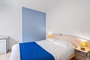 A bedroom with a bed, bedside tables, and a nightstand with a lamp. - Scenic 6-person Duplex Retreat (Île-aux-Moines)