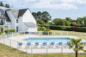 A swimming pool with lounge chairs, a white building, and a well-maintained garden. - Scenic 6-person Duplex Retreat (Île-aux-Moines)
