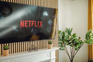 Ein Flachbildfernseher an einer Wand mit Holzpaneelen, eine kleine Topfpflanze und eine Fahrraddekoration darunter.