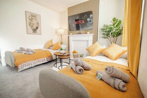 Ein Hotelzimmer mit zwei Betten, einem Fernseher, einem Kamin und einer Pflanze.