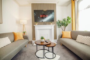 Ein Wohnzimmer mit zwei Sofas, einem Couchtisch, einem Kamin und einem an der Wand befestigten Fernseher.