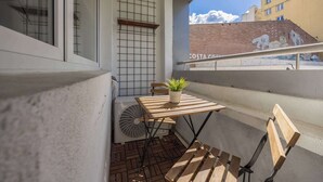 A balcony with a table, chairs, a potted plant, and a fan. - Air Conditioned Apartment in Center | Balcony (Warszawa)