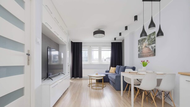 A modern living room with a sofa, dining table, and TV. - Air Conditioned Apartment in Center | Balcony (Warszawa)