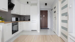 A modern kitchen with white cabinetry, a built-in microwave, and a black oven. - Air Conditioned Apartment in Center | Balcony (Warszawa)