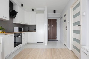 Eine moderne Küche mit weißen Schränken, einer eingebauten Mikrowelle und einem schwarzen Backofen.
