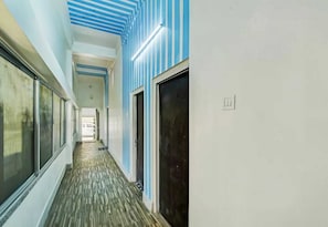 A hallway with striped walls, a patterned floor, and a door with a dark panel.