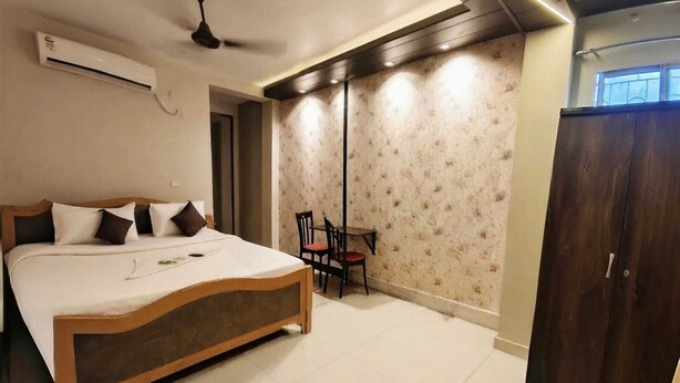 A bedroom with a bed, a desk, a wardrobe, and an air conditioning unit. - Nilay Guest House (Kolkata)