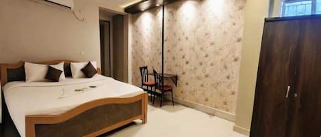 A bedroom with a bed, a desk, a wardrobe, and an air conditioning unit.