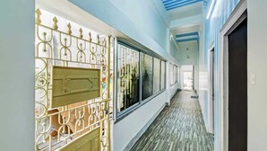 A corridor with a metal gate, large windows, and a ceiling with blue beams. - Nilay Guest House (Kolkata)