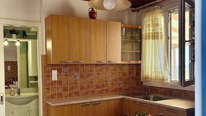 Eine Küche mit Holzausstattung, gefliestem Fliesenspiegel, einer Spüle und einem Fenster mit Vorhang.