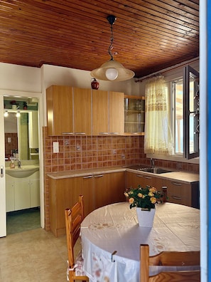 Eine Küche mit Holzausstattung, gefliestem Fliesenspiegel, einer Spüle und einem Fenster mit Vorhang.