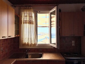 A kitchen with a window, a sink, and cabinets. - LOTOS SUITE (Kini)
