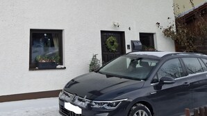Ein Gebäude mit weißer Fassade, zahlreichen Fenstern und einem geparkten Auto davor.