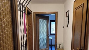 Ein Flur mit Holzboden, einer Bank und einer Tür mit Fensterteil.