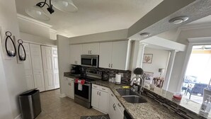 A kitchen with white cabinets, a granite countertop, stainless steel appliances, and a trash can. - Beautiful 3-bedroom House in New Tampa (Tampa)