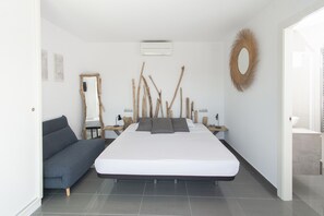 Ein modernes Schlafzimmer mit einem großen Bett, einer Couch, einem Spiegel und einem Wandbild.