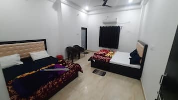 A room with two beds, a ceiling fan, an air conditioning unit, and a door.