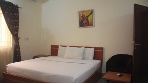 Ein Schlafzimmer mit Bett, Nachttisch, Sessel und einem Bild an der Wand.