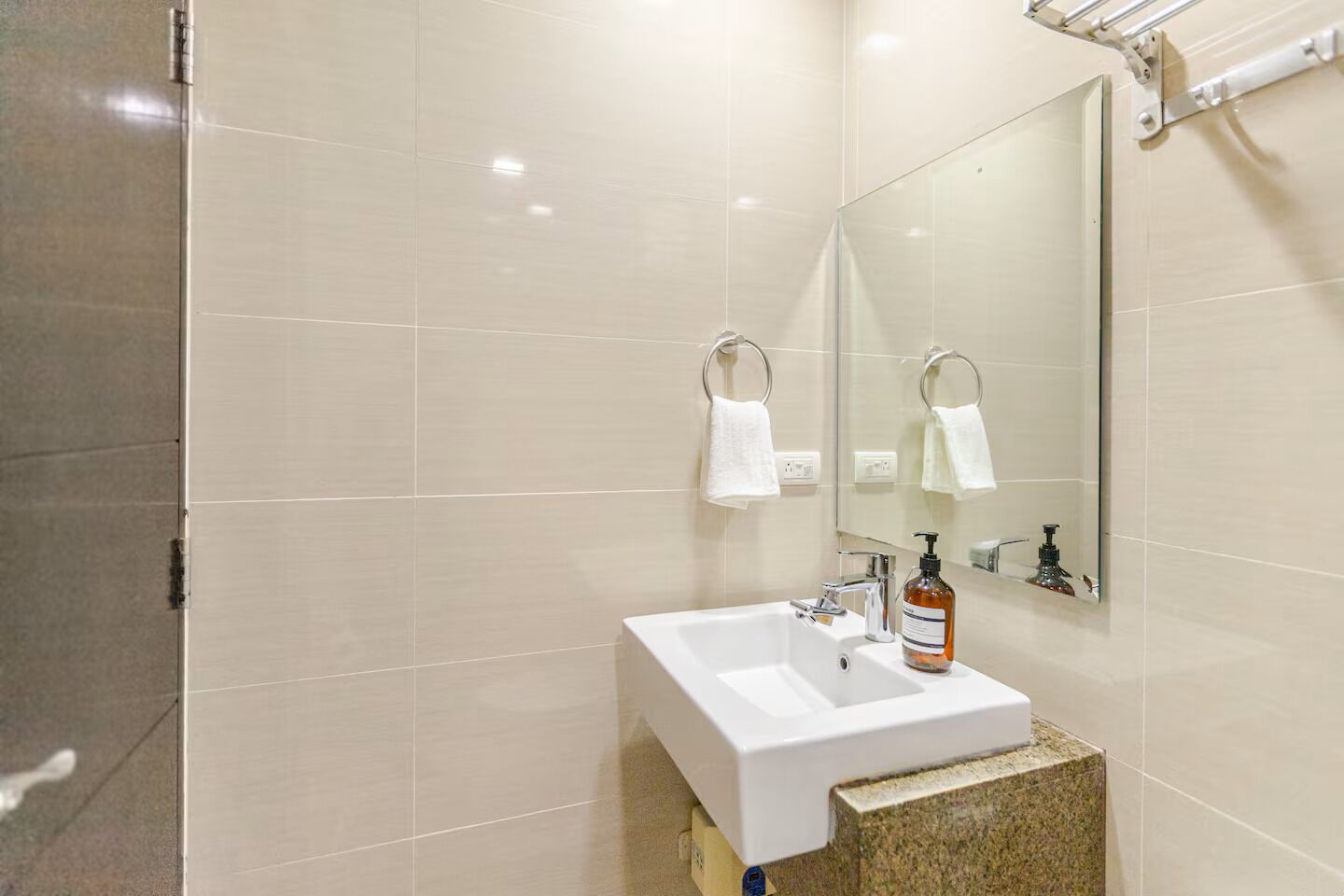 Une salle de bain moderne avec un lavabo blanc, un miroir et un porte-serviettes.