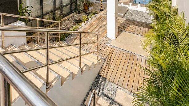 A modern outdoor area with a wooden deck, a pool, and potted plants. - BNEW! Cozy 1-BR Studio in High End Makati with Pool, Gym, Jacuzzi, Sauna (Makati)