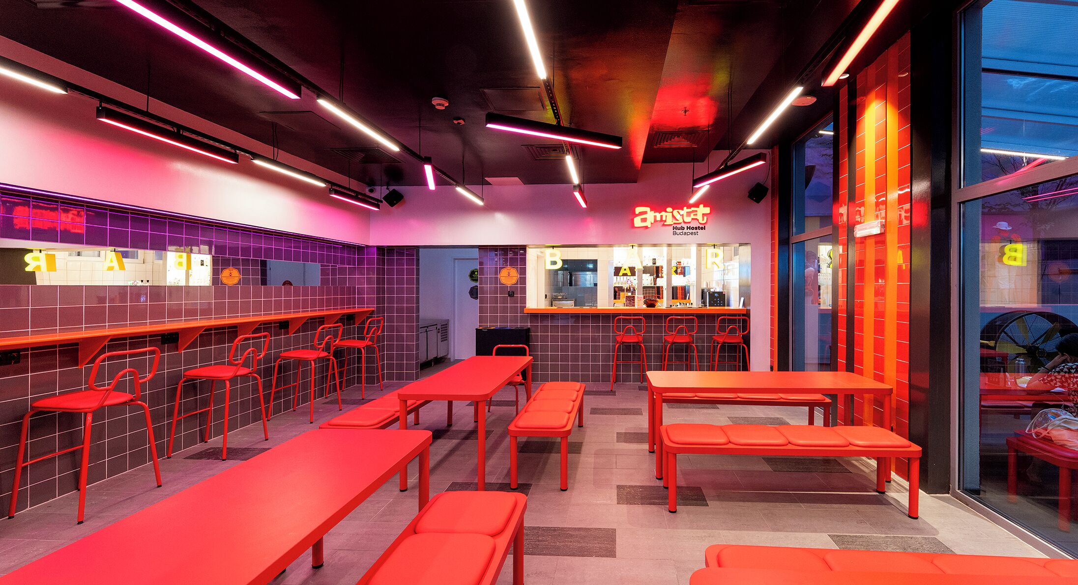 Un espacio interior bien iluminado con asientos rojos y una zona de bar.