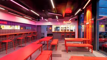 Un espacio interior bien iluminado con asientos rojos y una zona de bar.