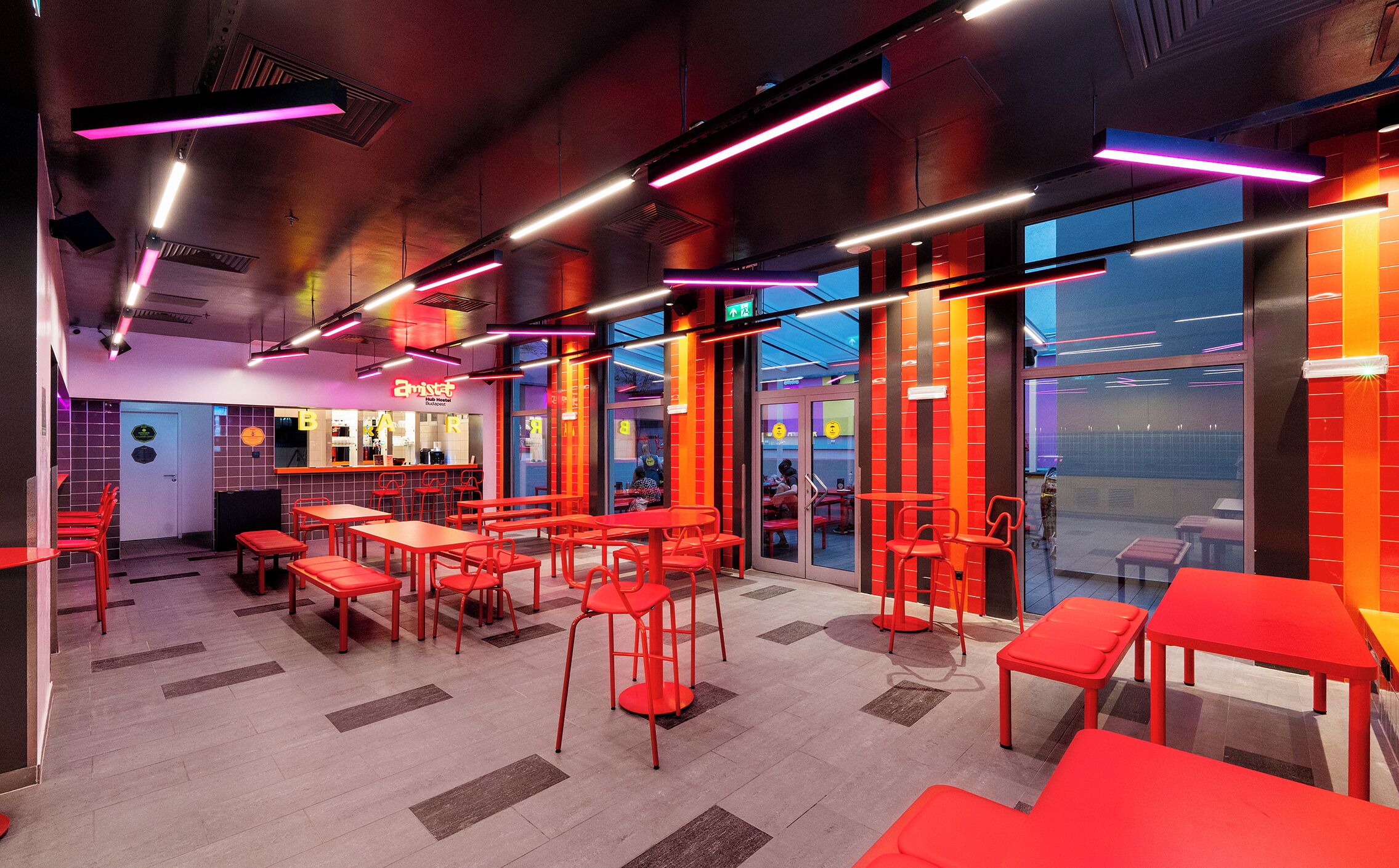 A modern interior with red furniture, neon lights, and large windows.