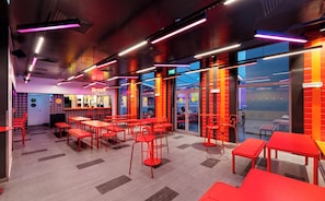 Un interior moderno con mobiliario rojo, luces de neón y grandes ventanales.