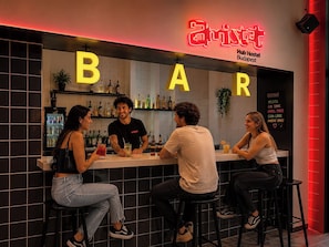 Una zona de bar con un letrero de neón, un panel de menú y un refrigerador lleno de bebidas.