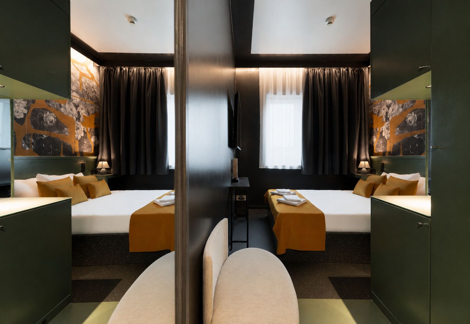 A mirrored hotel room with two beds, a desk, and a large mirror.